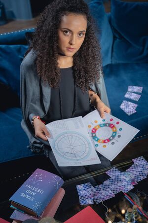 Young pretty woman holding natal charts in both handsの写真素材