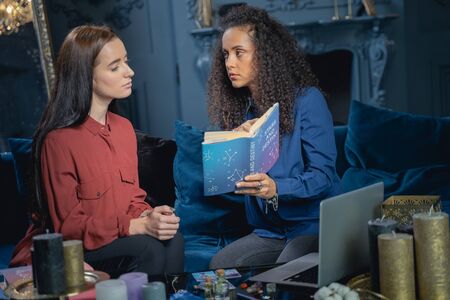 Beautiful astrologer explaining an extract in a book to a woman
