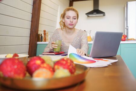 Let me check. Charming blonde female looking at color palette while thinking about great resultの写真素材