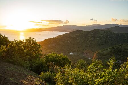Beautiful landscape of green tees, mountains and sea with bright morning sky on background stock photoの写真素材