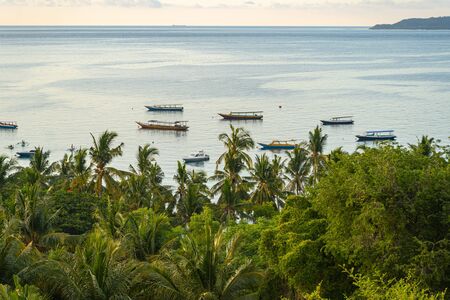 Boats are sailing in calm ocean bay behind junglesの写真素材