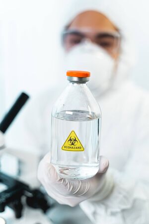 Dangerous liquid. Silhouette of young scientist that covering his face with protective mask and glassesの写真素材
