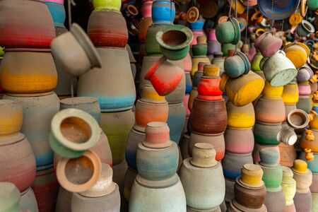 Exotic pottery. Colorful clay goods being on the foreground, local market inviting tourists for...