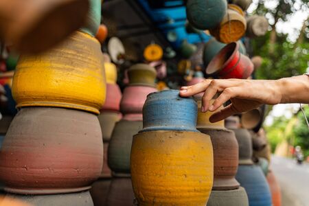 Local pottery. Young female person stretching her hand while going to buy blue pot for herselfの写真素材
