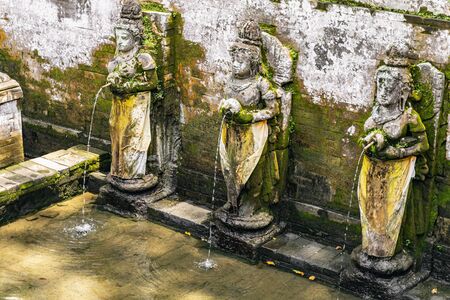 Balinese architecture. Old fountain being decorated with creative sculptures of goddesses in the exotic countryの写真素材