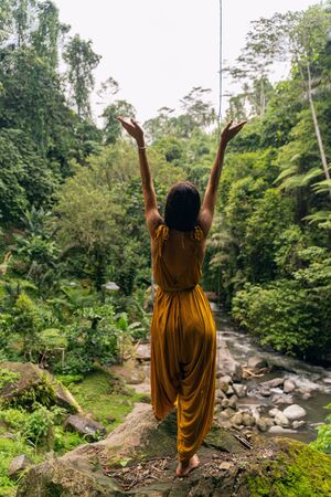 Power of nature. Pleased girl raising her arms while breathing with clean air and enjoying tropical climateの写真素材