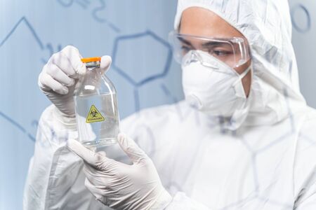 Serious Asian researcher wearing protective uniform while contacting with chemical reagents during...