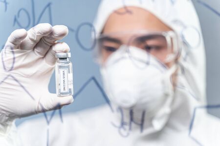 Virus vaccine. Professional male person covering his face with respiratory mask while inventing...