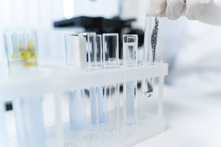 Close up of hand that taking test tube from support, science and research concept