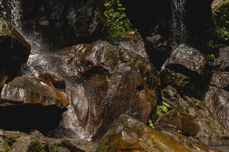 Splashing water. Focused photo on wet rocks that being on the foreground, drops of waterfallの写真素材