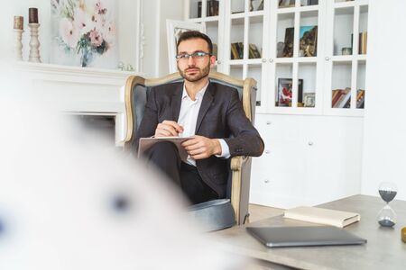 Front view of a calm attractive elegant young man in eyeglasses looking at the cameraの写真素材