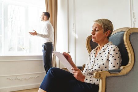 Side view of a focused Caucasian female psychotherapist assessing a young male patients emotional stateの写真素材