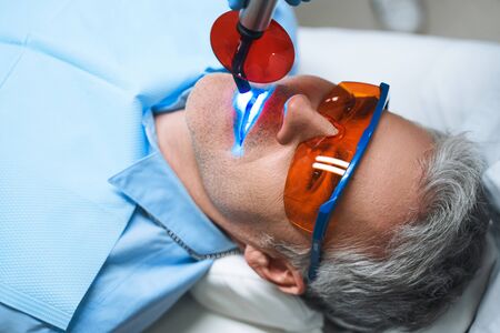 Male is lying in dental chair after being given root canal into tooth in modern clinicの写真素材