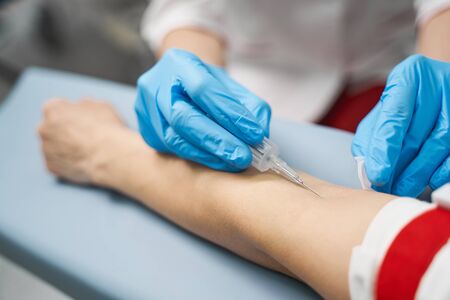 Focused photo on female hands that wearing sterile gloves while doing injection before taking blood sampleの写真素材