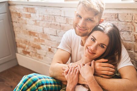 Feeling happiness. Handsome bearded man embracing his girlfriend while enjoying home weekend...