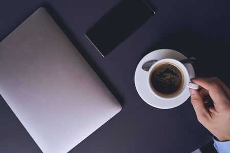 Top view of a male hand lifting a cup of hot espresso from the saucerの写真素材