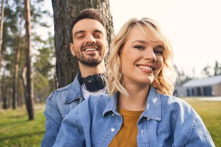 Portrait of two smiling young Caucasian people in denim jackets looking in front of themの写真素材