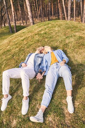 Joy and happiness. Low angle of two modern loving young people lying on the grass