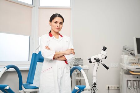 Cheerful female doctor wearing medical uniform while working with patients in modern clinicの写真素材