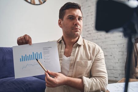 Serious male entrepreneur with a pen in his hand showing a profit growth bar chartの写真素材