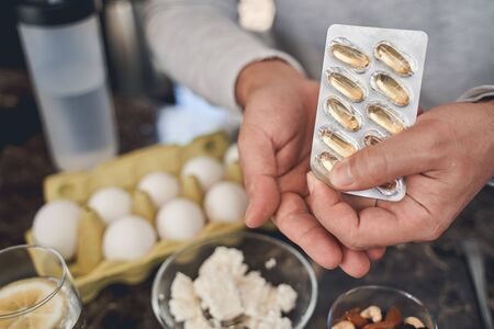 Cropped photo of a Caucasian male holding a blister pack of omega-3 fish oil capsulesの写真素材
