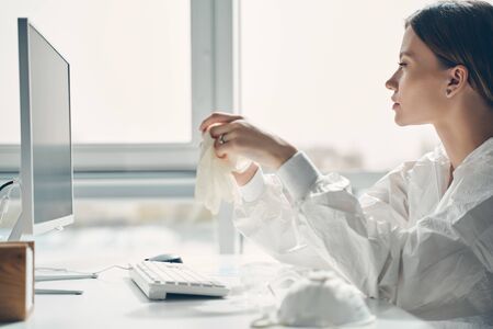 Cropped photo of beautiful young woman in protective suit holding sterile gloves while working in...