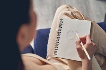 Close up of lady hand making sketch of female face in spiral artist sketchpad