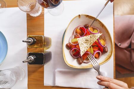 Close up of lady holding fork and knife while sitting at the table with delicious vegetarian lunchの写真素材