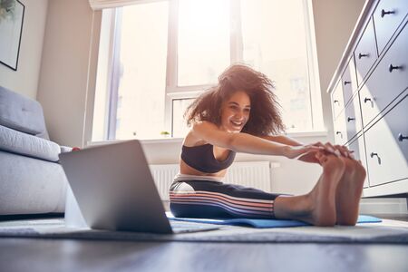 Emotional brunette female keeping smile on her face while doing sport at home