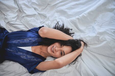 Top view of pleased international female demonstrating her friendly smile while having rest at homeの写真素材