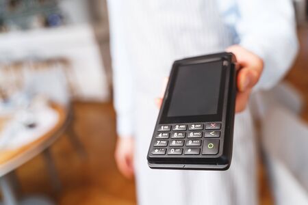 Close up of male waiter hand with contactless card machine for various types of payments