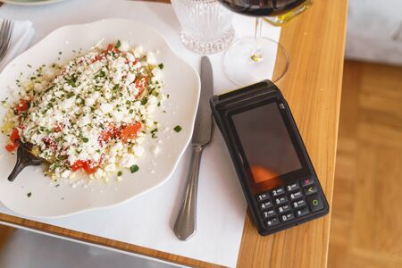 Top view of delicious food, knife and terminal for contactless payment on wooden tableの写真素材