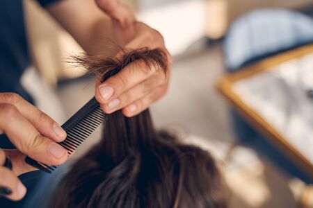 Close up of hairdresser black comb with dark brown hair for little child at homeの写真素材