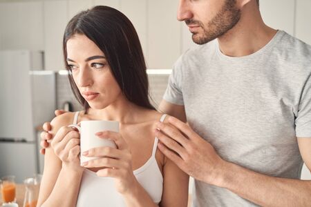 Young man embracing warmly and carefully pretty woman while making her understand that she is not aloneの写真素材