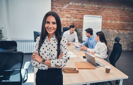 Happy business posing in modern office at workplace with her colleagues on the backgroundの写真素材