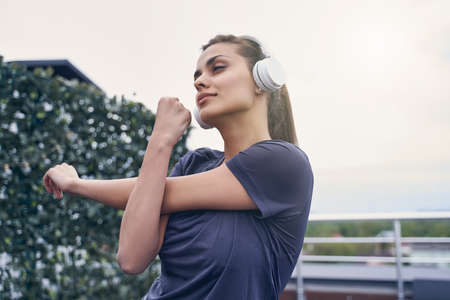 Attractive sporty lady working out and listening to music through wireless headphones