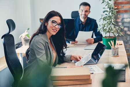Beautiful business lady looking at the camera and smiling while working in officeの写真素材