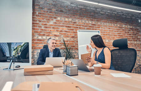 Beautiful young business woman and handsome businessman in business suit are using gadget