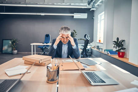 Businessman with desperate of facial expression sitting at the wood table in his workplaceの写真素材