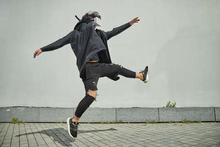 Stylish guy in black outfit using VR headset and doing tricks in the air