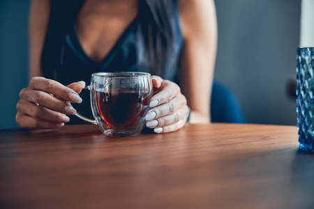 Close up portrait of hand female with mug of black tea in the office kitchenの写真素材