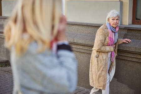 Full length portrait of old female holding hand on stomach while looking on lady near herの写真素材