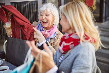 Happy two ladies holding new casual clothes while feeling happy on the weekend