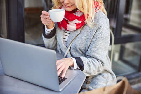 Close up portrait of smiling woman drinking cup of coffee while sitting at the street cafeの写真素材