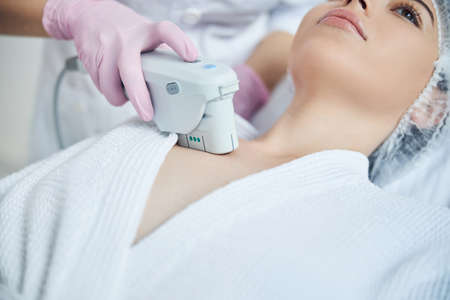 Pretty lady getting decolletage skin rejuvenation while resting on couchの写真素材