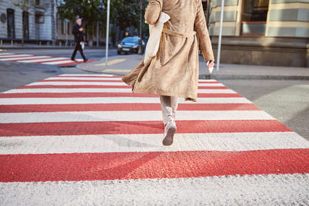 Cropped head portrait of female dressed brown coat walking through the old streetの写真素材