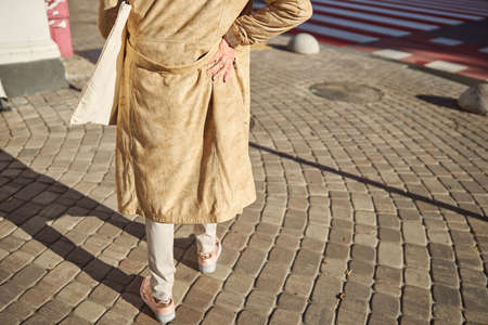 Cropped head portrait of woman wearing brown coat with white handbag on the shoulderの写真素材