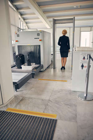 Elegant businesswoman in skirt suit passing through check-in gate before the flight