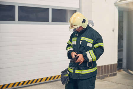 Waist up portrait of strong male before performing rescue and extinguishing while holding protective gloves in handsの写真素材