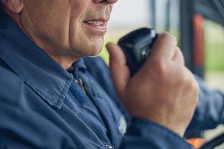 Cropped head portrait of adult man talking on the walkie talkie with fire station
